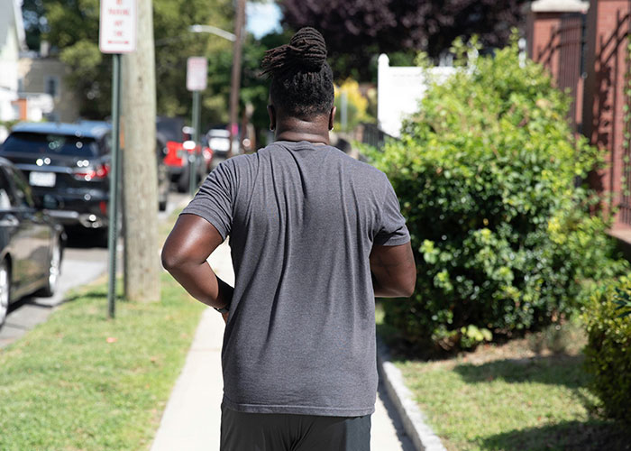 Person walking on sidewalk in a suburban area, highlighting frivolous police calls.