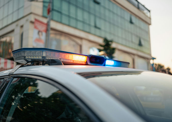 Police car with flashing lights in front of a building during a call for a non-serious reason.