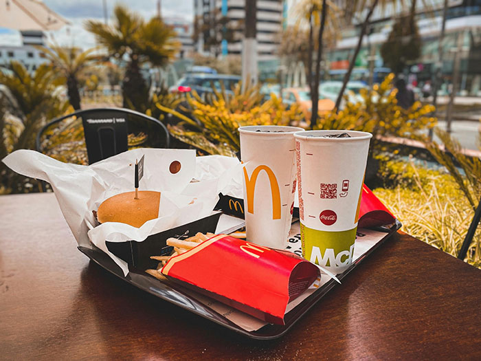 Fast food tray with burger, fries, and drinks outdoors, highlighting wheat allergy concerns.