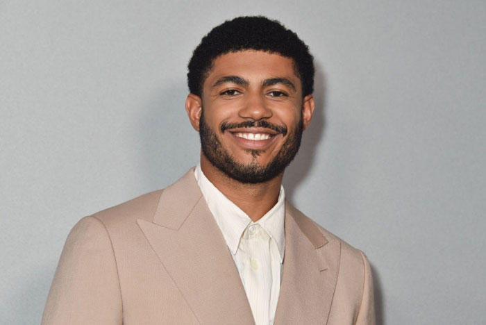 Smiling man in a beige suit and white shirt, representing the "Tell Me Lies" cast for season 2 drama.