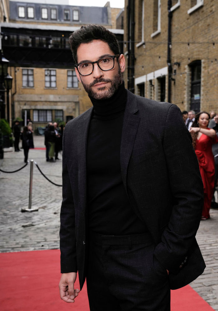 Man in a dark suit on a red carpet, representing Tell Me Lies cast in a street setting.