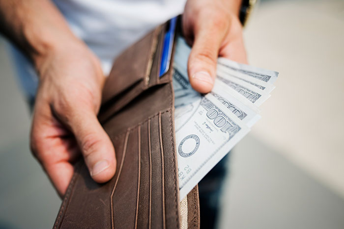 Person holding a wallet with dollar bills, representing a legal win against a greedy landlord.