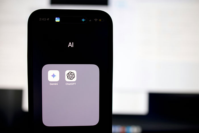 Smartphone displaying AI folder with ChatGPT and Gemini apps on screen.