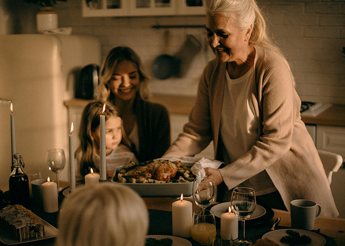 Family serving Thanksgiving turkey with candles on the table.