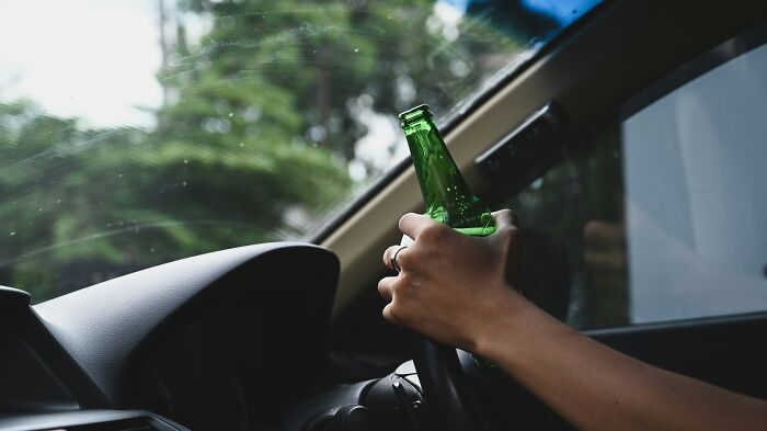 Person holding a green bottle while driving a car, illustrating a moment that altered partner perception.