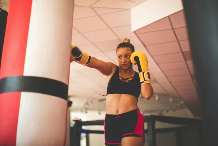 Woman boxing with gloves in a gym, focused and determined, engaging in an intense workout session.