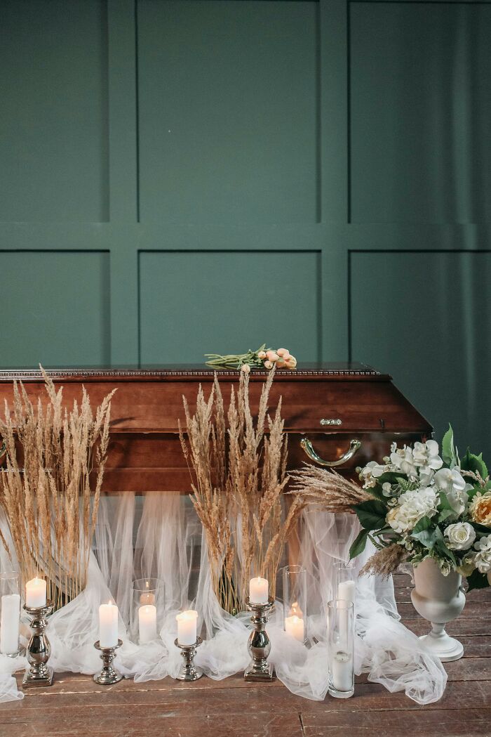 Casket adorned with flowers and candles, setting evokes a somber yet elegant atmosphere, highlighting a reverent moment.