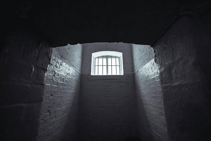 Dimly lit room with a small barred window, capturing unique atmosphere with rare lighting contrast.