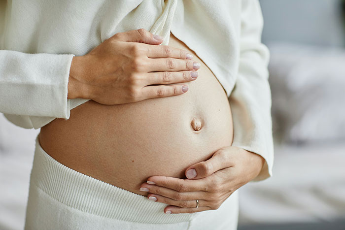 Pregnant woman in white clothing cradling her belly, symbolizing unique statistics and personal experiences.