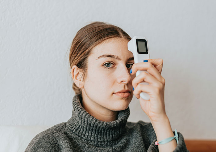 A woman in a gray sweater holds a device to her forehead, highlighting unique rare statistics.