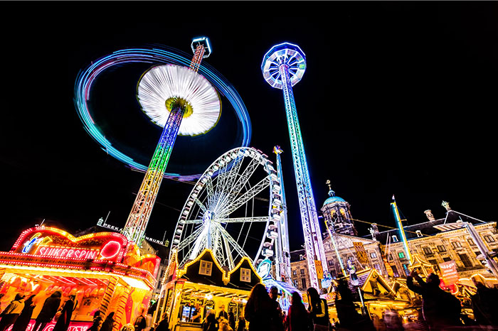 Colorful amusement park at night, featuring rides and attractions, representing things people bought as adults denied in childhood.