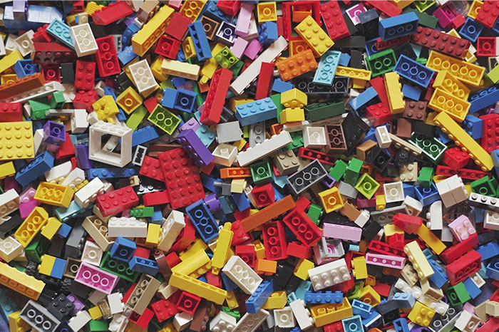 Colorful Lego blocks scattered on a surface, representing toys people bought as adults denied in childhood.