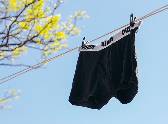 Black Puma underwear hanging outside, representing things bought as adults denied in childhood.