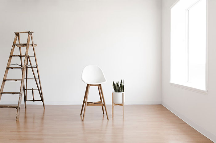 Minimalist room with a ladder, chair, and plant; items often bought by adults denied in childhood.