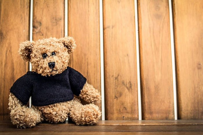 Teddy bear on wooden bench, symbolizing items adults buy when denied in childhood.