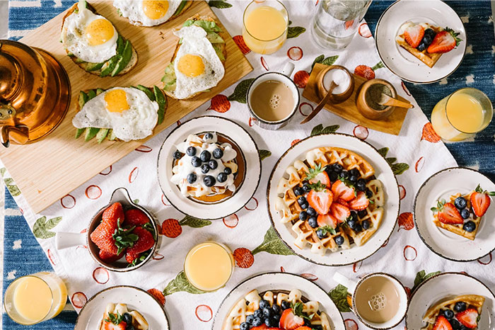 Breakfast spread with waffles, eggs, and fruit, representing indulgent things adults purchased after a deprived childhood.