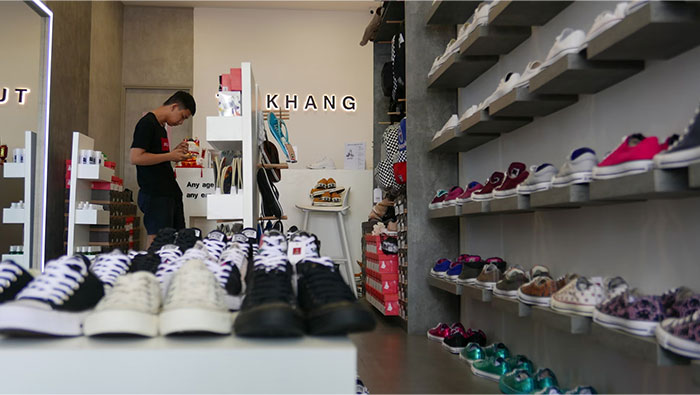 Adult browsing in a shoe store, surrounded by shelves of sneakers, symbolizing things denied in childhood.