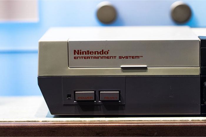 Nintendo Entertainment System on a wooden surface, often bought by adults who were denied it in their childhood.