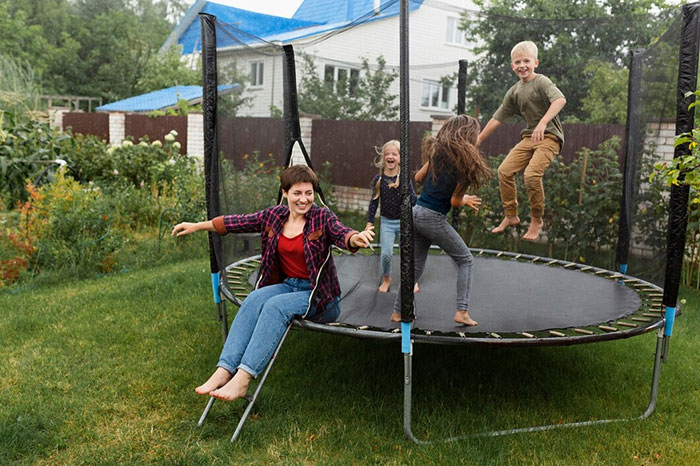 A woman and three kids enjoying a trampoline in a backyard, capturing things people bought as adults denied in childhood.