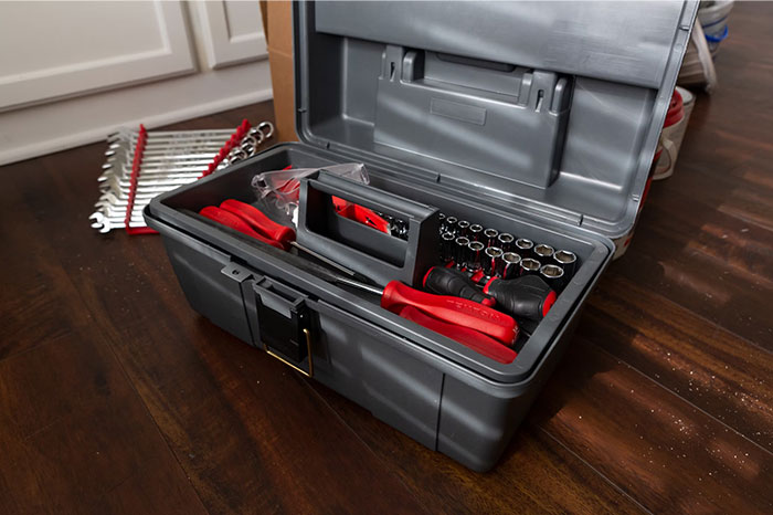 Toolbox filled with various hand tools on a wooden floor, representing things people bought as adults.