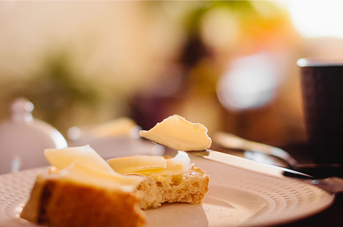 Butter spread on bread, a childhood-denied comfort food, on a plate in a softly lit setting.