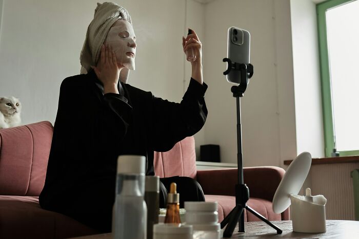 Person applying a face mask while recording themselves, highlighting things people judge others for in beauty routines.