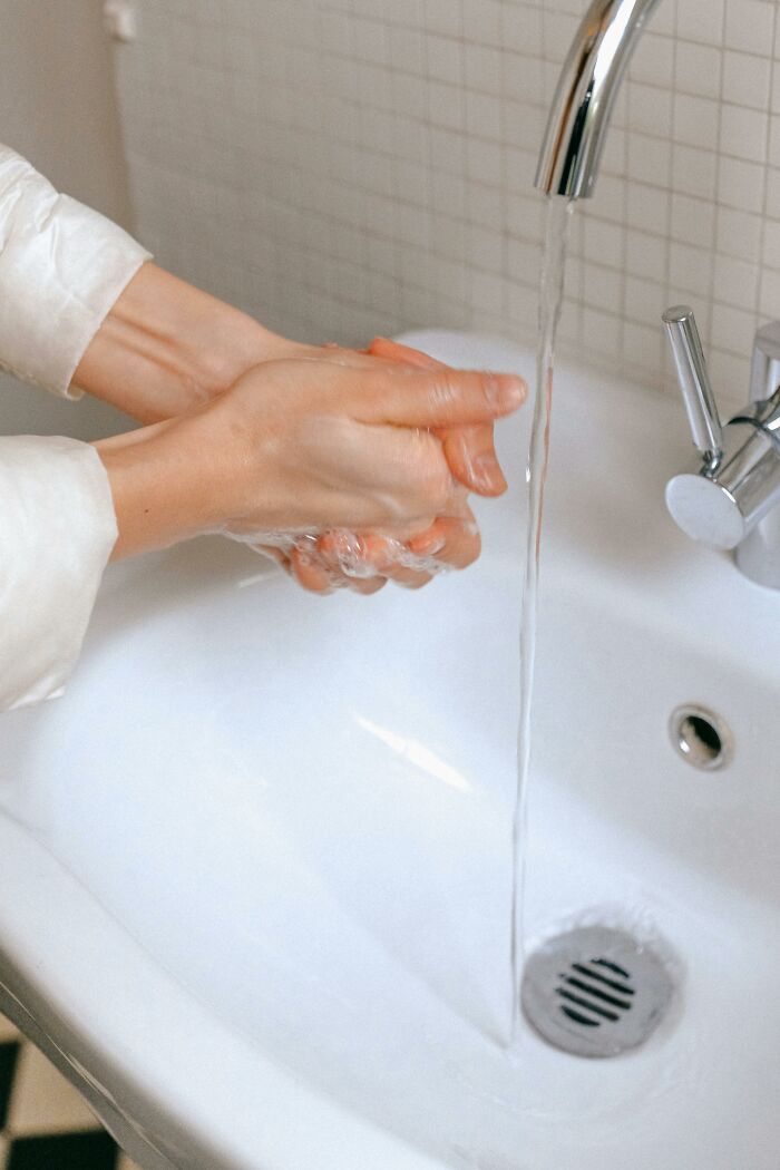 Hands being washed under a running tap, representing personal hygiene, a common aspect people judge others for.