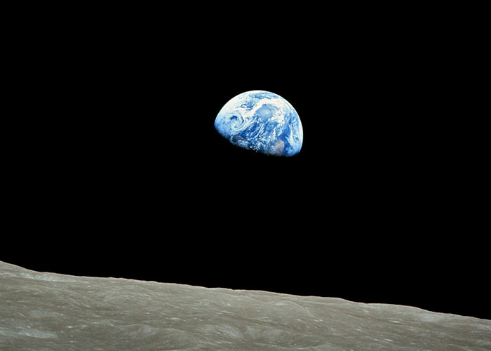 Earth rising above the moon's horizon, showing Earth's beauty and vastness in space.