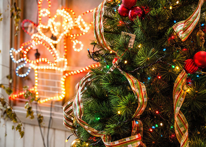 Christmas tree with colorful lights and ribbons, reindeer decoration in the background, highlighting terrible holiday decor.