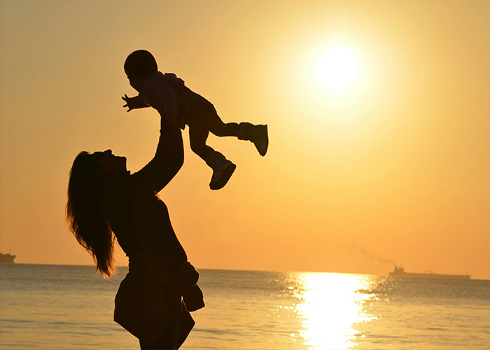 Silhouette of a person lifting a child at sunset by the sea, reflecting on the concept of things actually being terrible.