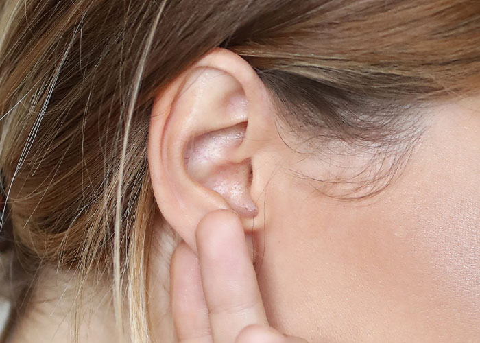 Close-up of a person's ear being touched, highlighting intriguing facts.