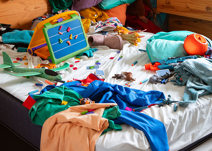 Messy bed with toys and clothes scattered, reflective of intriguing facts from the "Today I Learned" community.