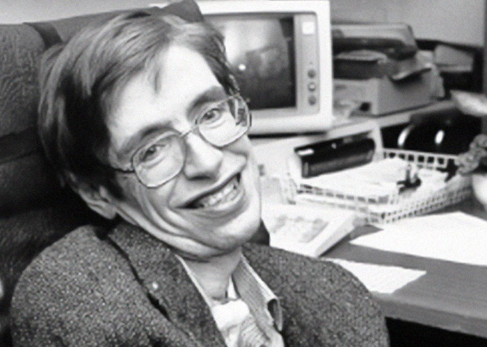 Man smiling in office setting with vintage computer, related to intriguing facts and learning community.