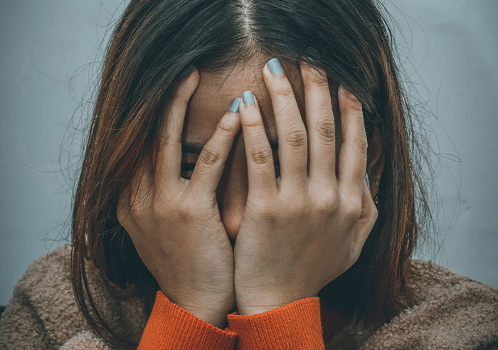 Woman covering her face with hands, illustrating toxic family dynamics.