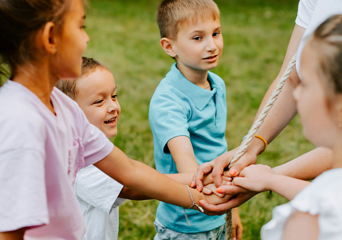 Children playing a teamwork game in a grassy area, demonstrating family dynamics and interaction.