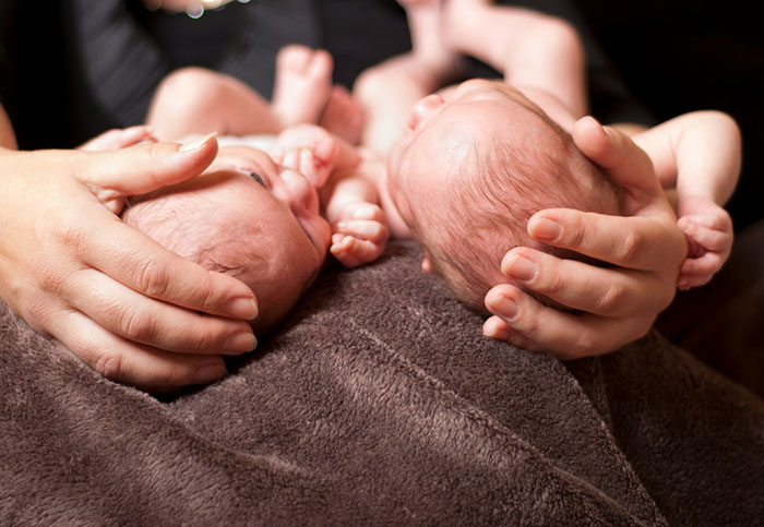 Hands gently cradling newborns, illustrating stories of insurance claims and personal experiences.