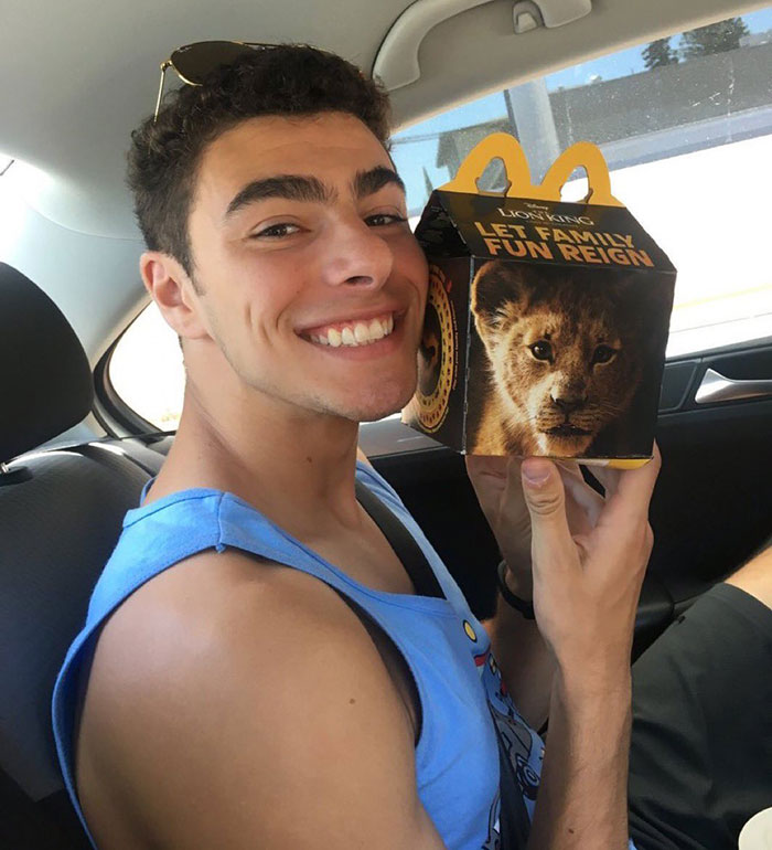 Luigi Mangione smiling with a "Lion King" themed McDonald's Happy Meal in a car, illustrating Luigi Mangione's concepts.