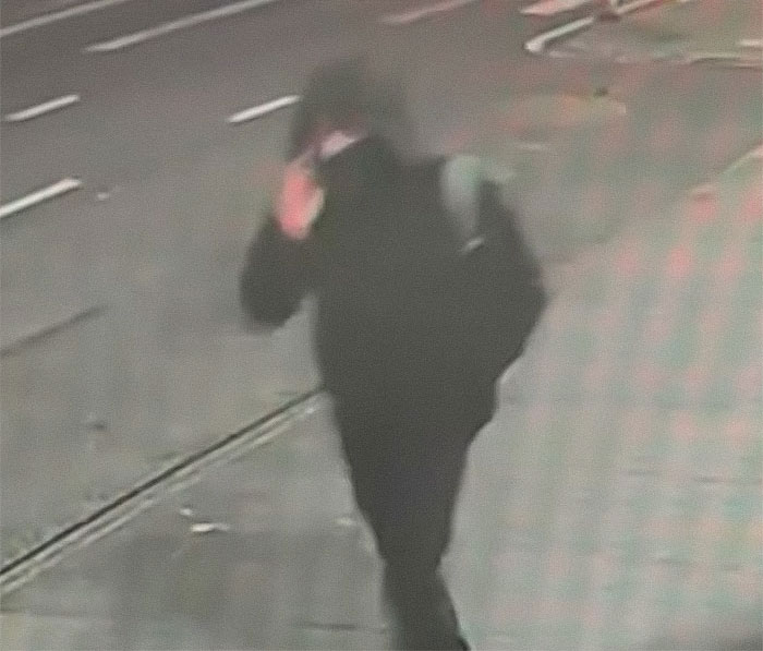 CCTV footage of a person in dark clothing on a street, related to Brian Thompson’s homicide case.