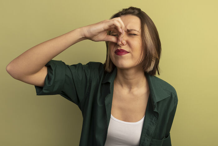 Person holding nose, reacting to smell; illustrates vegan family drama over neighbors cooking meat.