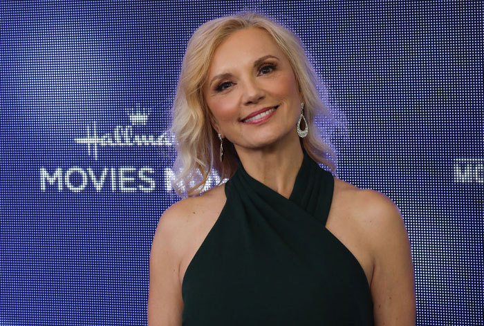 Blonde woman in a green dress from the Virgin River cast, smiling at a media event.