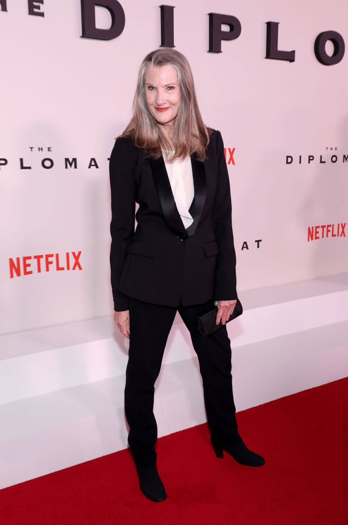 "Virgin River cast member in a black suit at a Netflix premiere, posing on the red carpet."