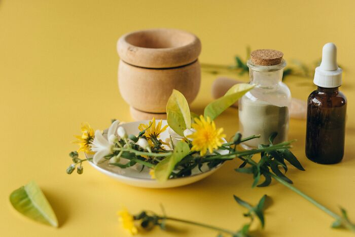 Natural ingredients with a mortar and pestle, small bottle, and dropper.