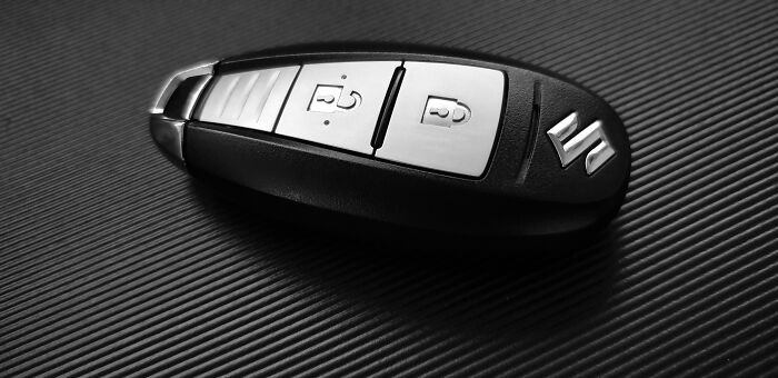 A car key fob with a sleek design placed on a dark textured surface.