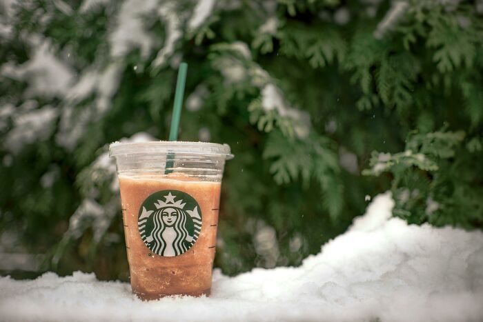 Starbucks iced drink cup in snow, highlighting luxury.