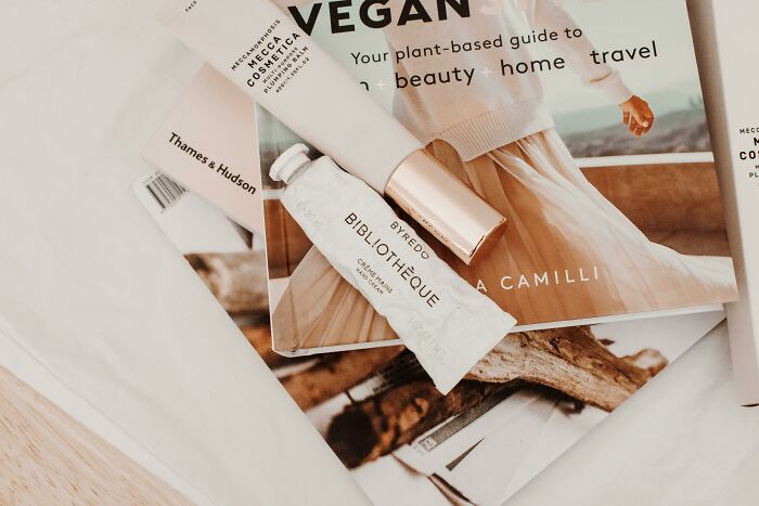 Cosmetic tubes and a lifestyle magazine on a wooden table, highlighting luxurious packaging.