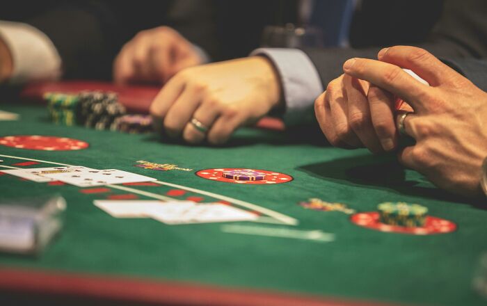 People playing poker at a casino table, featuring green felt and poker chips, representing exorbitant luxury.