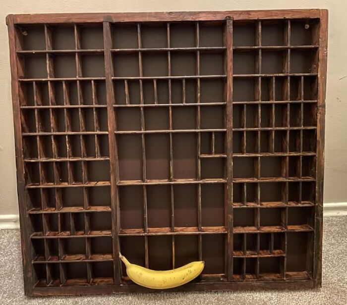 Second-hand wooden display case with grid pattern, featuring a yellow banana at the bottom, representing strange discoveries.