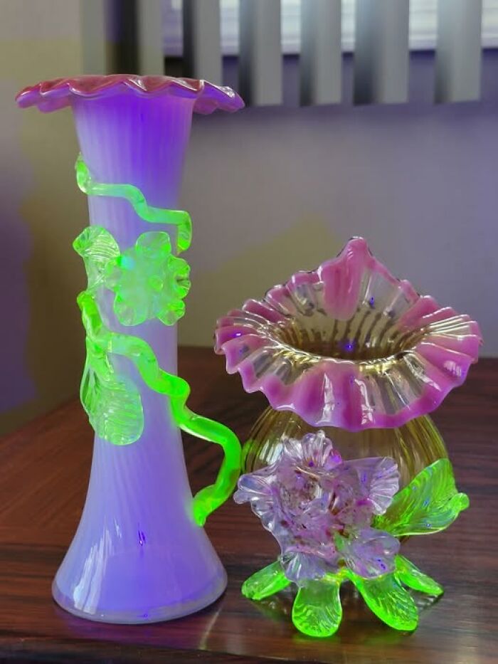 Strange and spectacular second-hand glass vases with vibrant green and purple accents on a wooden table.