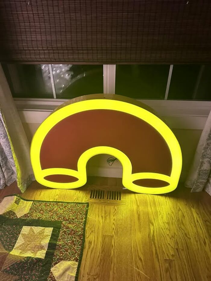 Strange second-hand discovery of a bright yellow and red retro-style sign on a wooden floor.