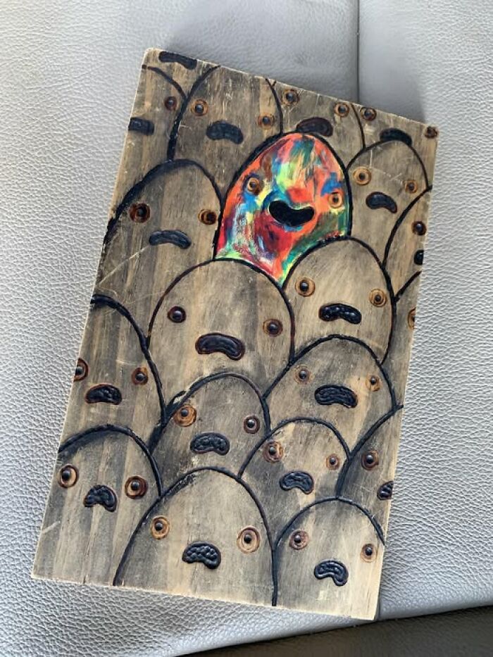 Strange and spectacular artwork featuring numerous wooden faces with one colorful face standing out.